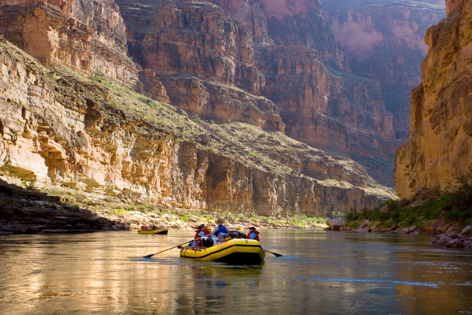 OARS rafts in calm water surrounded by huge cliffs in Grand Canyon