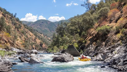 An OARS raft floating through a rocky section of the Wild & Scenic Tuolumne River